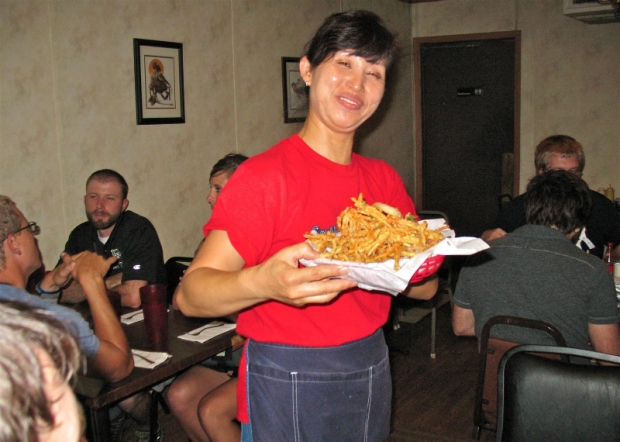 The smiling face of Kitok&#039;s, Kyung Brendemuehl, shows off a basket of Kitok&#039;s famous oriental fries before serving them to a table of happy patrons.